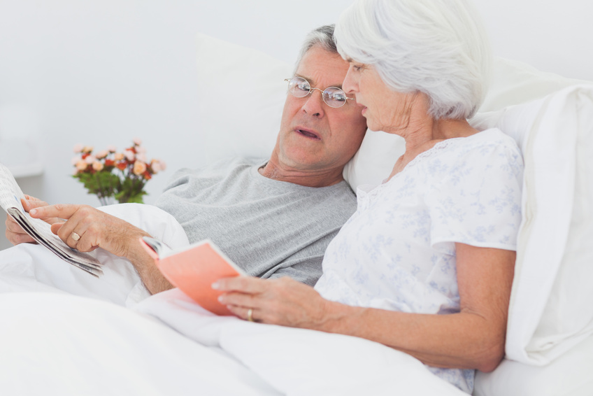 Mature couple looking at a newspaper in bed